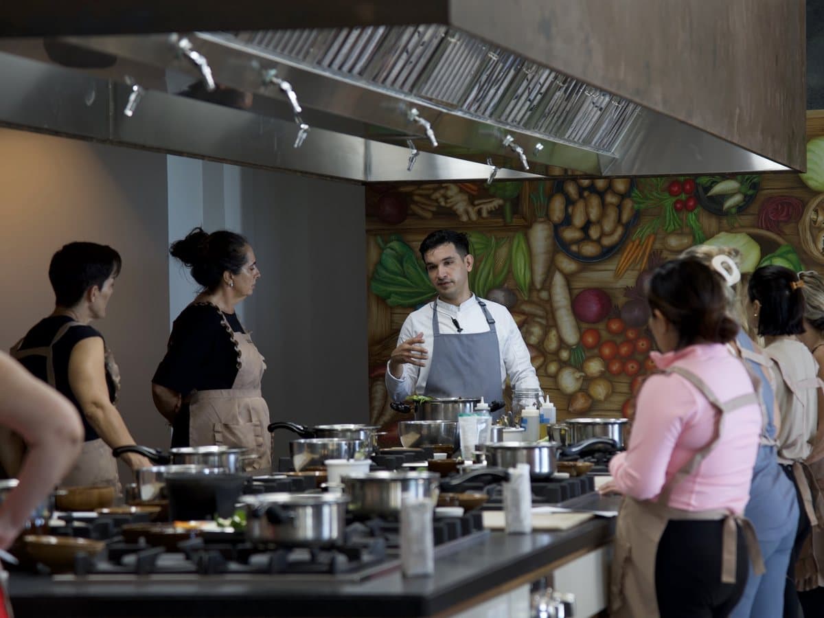 Guests in aprons at a cooking class, gathered around the chef